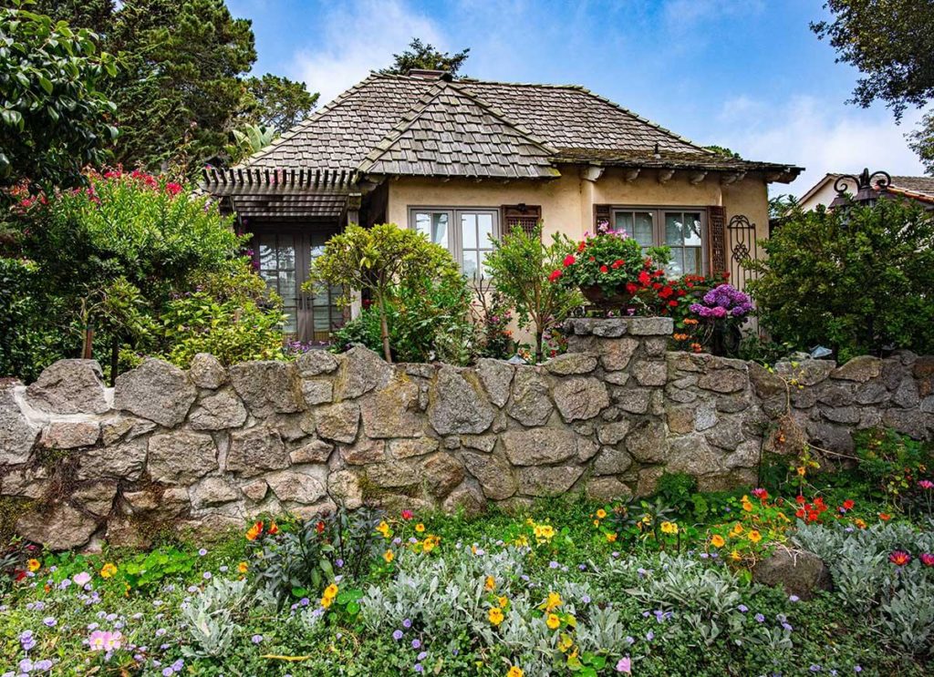 Gorgeous stone wall and greenery in front of cozy Carmel By The Sea cottage