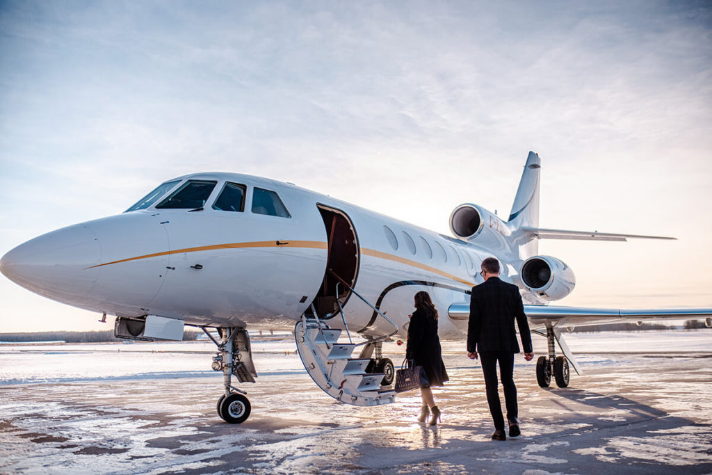 Business man and woman approach private turbo jet charter for business travel.